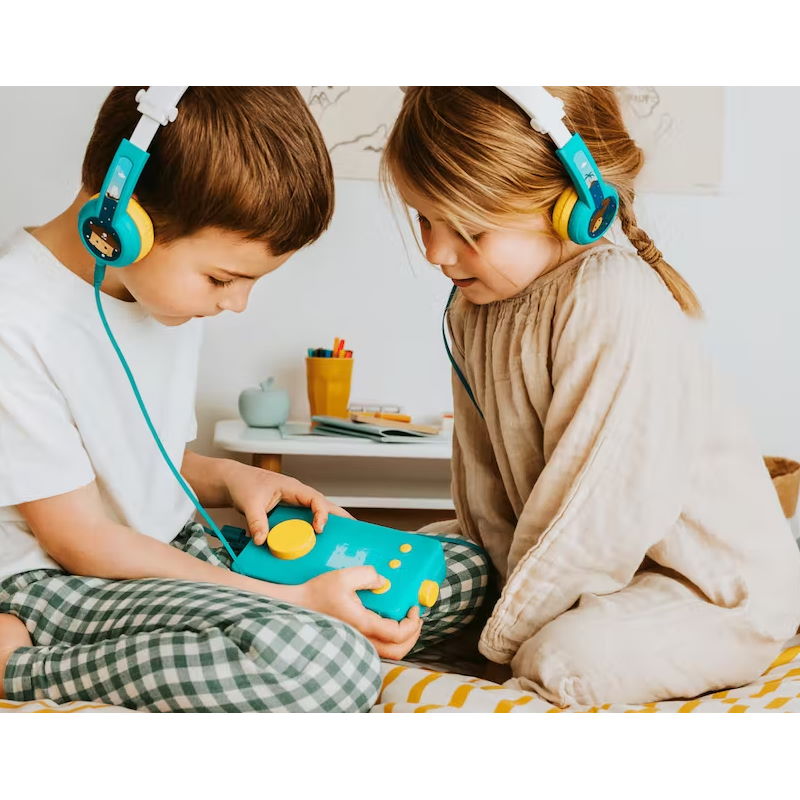 deux enfants assis sur un lit, ils ont tous les deux un casque sur les oreilles et écoutent une histoire de la boîte à histoires Lunii